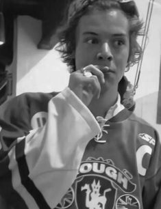 a young man is brushing his teeth while wearing a sweatshirt