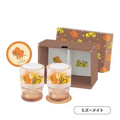 two glass cups in front of a box with an orange and yellow design on it