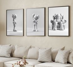 three black and white pictures hang on the wall above a couch in a living room