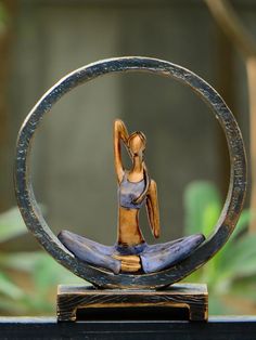 a figurine sitting on top of a circular object in the shape of a woman doing yoga