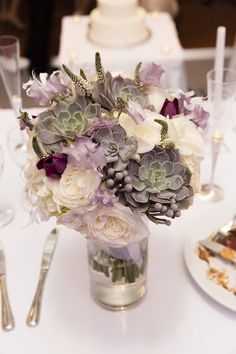 a vase filled with flowers sitting on top of a table next to plates and silverware