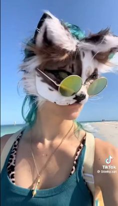 a woman wearing sunglasses and a cat mask on the beach