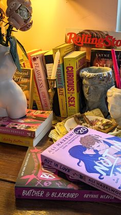 several books on a table next to a vase with flowers in it and other items