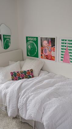 a white bed sitting in a bedroom next to two pictures on the wall above it