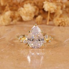 a pear shaped diamond ring sitting on top of a counter