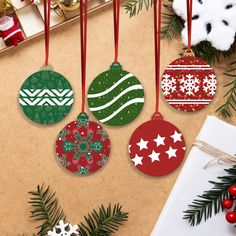 four christmas ornaments hanging from a tree with red and green baubles on them