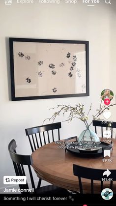 a dining room table with flowers in a vase on it and an image above the table