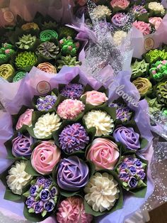 there are many different cupcakes in the bouquet on this table, each decorated with flowers and ribbons