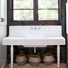 a white sink sitting under a window next to baskets