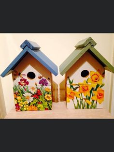 two bird houses with flowers painted on them sitting on a shelf next to each other