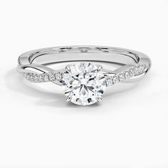 a white gold engagement ring with diamonds on the band and a round cut diamond in the center