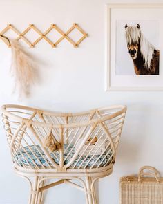 a wicker chair next to a white wall with pictures on it and a basket