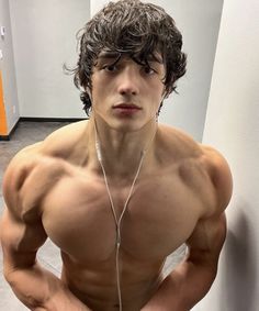 a shirtless young man with headphones on posing for a photo in the bathroom