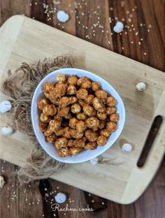 a white bowl filled with popcorn on top of a wooden cutting board