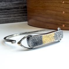 This stunning bracelet is handcrafted with both silver and gold elements, creating a unique and elegant design. The tension cuff style offers a secure fit with an easy-to-use clasp, making it the perfect accessory for any occasion. Great worn alone or stacked with other bracelets. I used an ancient technique called Keum-boo to fuse the 24k gold foil to the bracelet. Both heat and pressure are used to produce a diffusion bond between the silver and gold. The bracelets focal point is a hand fabric Luxury Cuff Bracelet With Patina, Modern Gold Bracelets With Sterling Silver Clasp, Modern Bangle Bracelet With Sterling Silver Clasp, Modern Sterling Silver Clasp Bangle Bracelet, Modern Bracelets With Box Clasp For Gifts, Adjustable Gold Bracelets With Sterling Silver Clasp, Luxury Adjustable Bracelet With Open Band, Luxury Adjustable Open Band Bracelet, Modern Bracelets With Hidden Clasp For Gifts