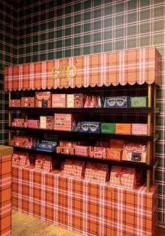 an orange and pink display case with boxes on the bottom, in front of plaid wallpaper