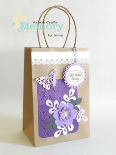 a brown paper bag with purple flowers and butterfly tags on it's handles, hanging from a string