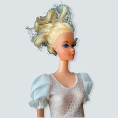 a doll with blonde hair wearing a white dress