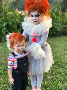 two children dressed up as clowns standing in the grass with their hands on each other's hips