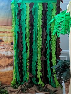 green and brown paper streamers hanging from the side of a curtain in front of a painting