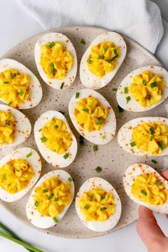 deviled eggs are arranged on a plate with chives