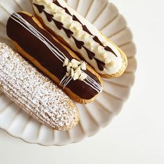 three pastries on a plate with powdered sugar and chocolate drizzles