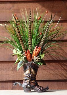 a vase filled with lots of flowers on top of a wooden table next to a wall