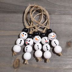 a group of snowmen hanging from a rope on top of a wooden table next to some balls