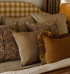 a bed topped with lots of pillows on top of it's headboard next to a window