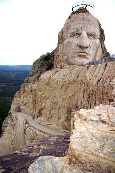 there is a large head on the side of a mountain with a bridge going over it