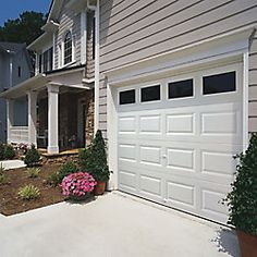 a house with two garage doors and flowers in the front garden area next to it