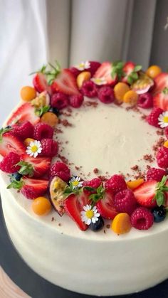 a white cake topped with fresh fruit and flowers