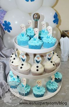 a three tiered cake stand with cupcakes and frosting decorations on it