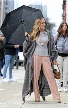 a woman is walking down the street with an umbrella in her hand and holding a purse