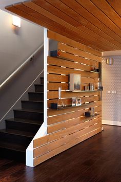 a room with wooden walls and stairs in the center, along with pictures on the wall