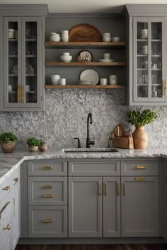 a kitchen with gray cabinets and marble counter tops, gold pulls on the cupboards