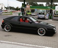 a black car parked in front of a gas station