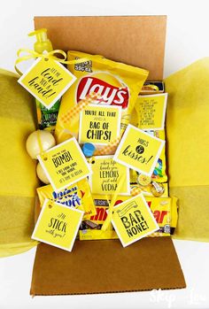 a yellow box filled with lots of different types of food and candy bars on top of a pillow