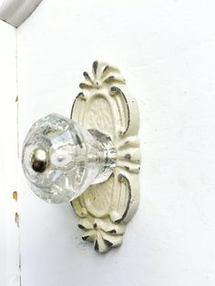 a glass door handle on the side of a white building with an ornate design and knob