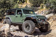 a green jeep driving down a rocky trail