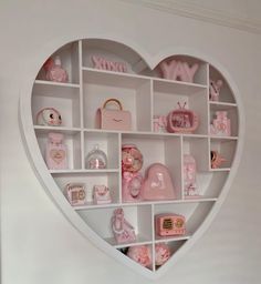 a heart shaped shelf filled with lots of pink items on top of a white wall