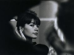 a black and white photo of a woman holding her hand up to her ear while looking at herself in the mirror