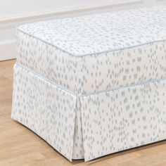 a blue and white bed skirt sitting on top of a wooden floor