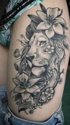 a woman's thigh with a lion and flowers tattoo on the side of her leg