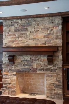 a living room with a stone fireplace and built in bookshelves