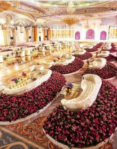 an elaborately decorated banquet hall with white couches and pink flowers on the floor