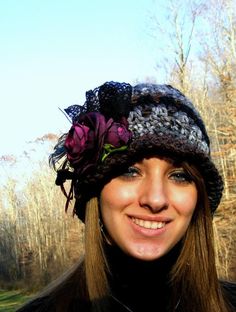 a woman wearing a knitted hat with flowers on the brim, smiling at the camera