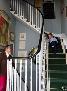 a young boy is climbing the stairs in a house with green carpet and white railings