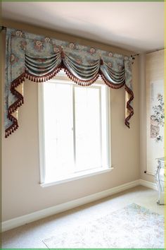 an empty room with a large window and curtained valance on the windowsill