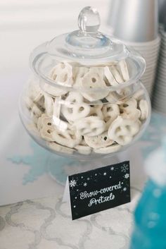 a glass bowl filled with white pretzels on top of a blue table cloth